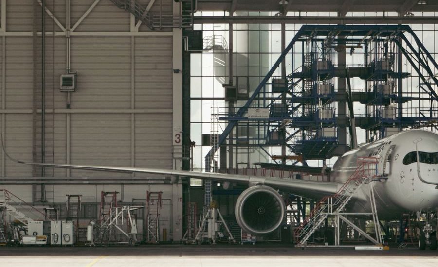 Detailed view of a commercial airplane undergoing maintenance inside an industrial hangar.