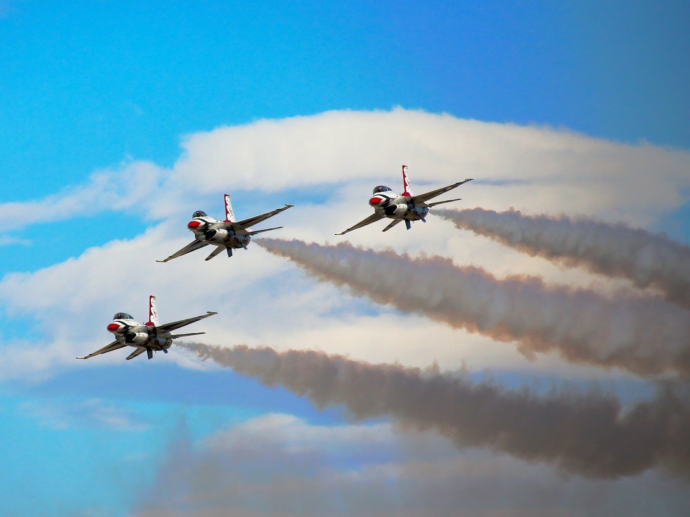 Photo by Simon Hurry a group of fighter jets flying through a cloudy blue sky